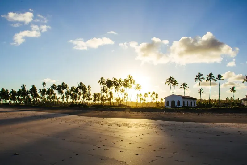 A capela na praia ao pôr do sol, entre coqueiros