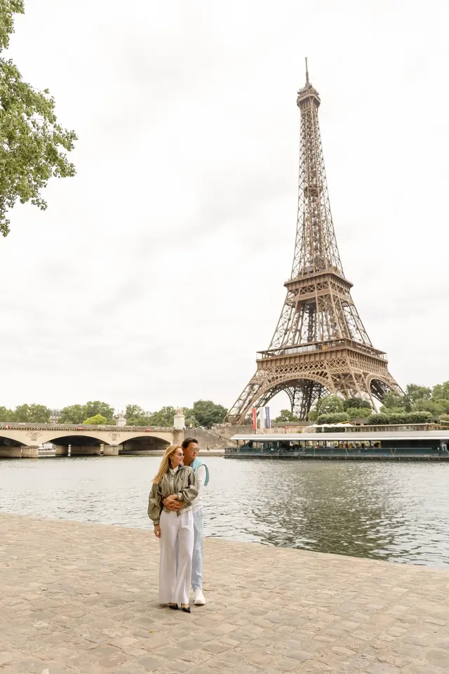 Thais e Marcos abraçados às margens do Sena, com a Torre Eiffel ao fundo