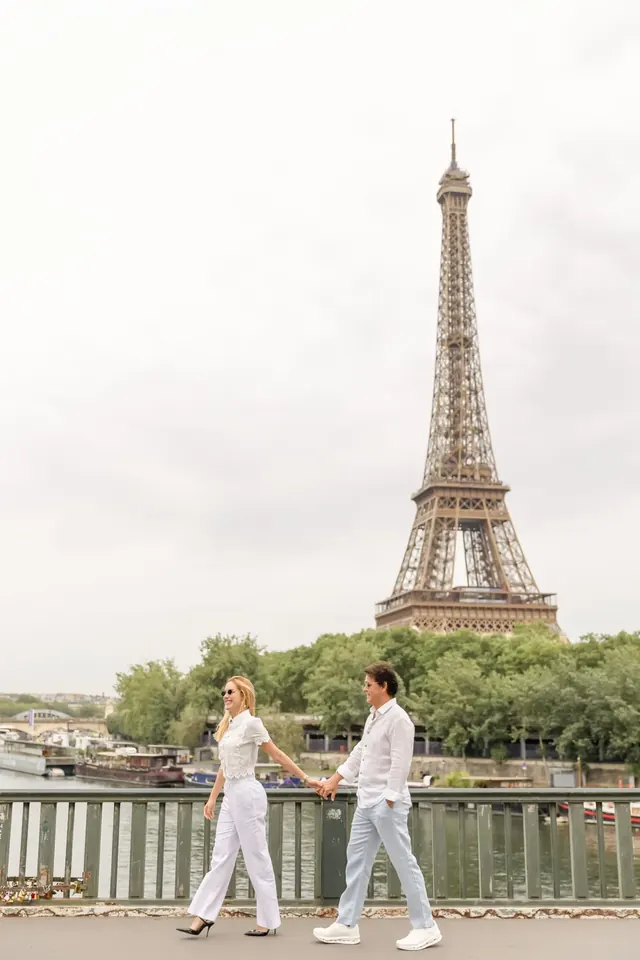 Thais e Marcos caminhando em uma ponte com a Torre Eiffel ao fundo