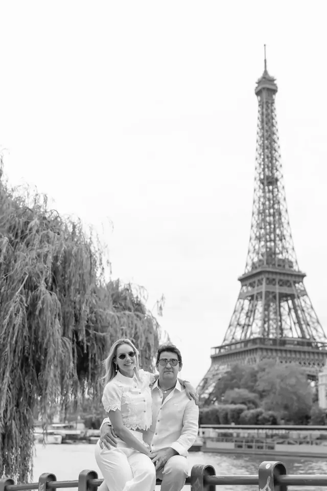 Thais e Marcos sentados juntos, em preto e branco, diante da Torre Eiffel